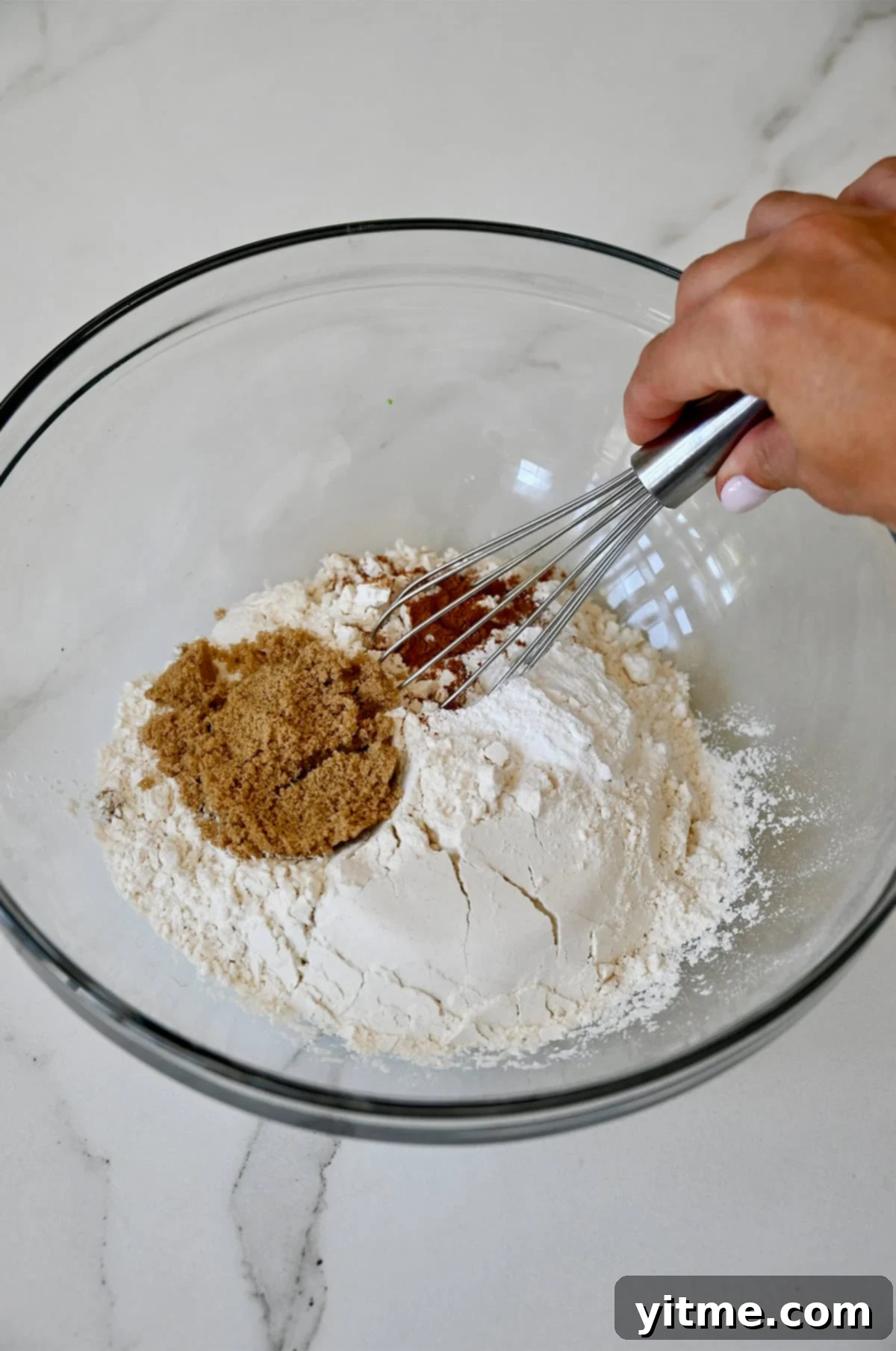 Whisking flour, cinnamon, brown sugar and baking powder together in a glass bowl.