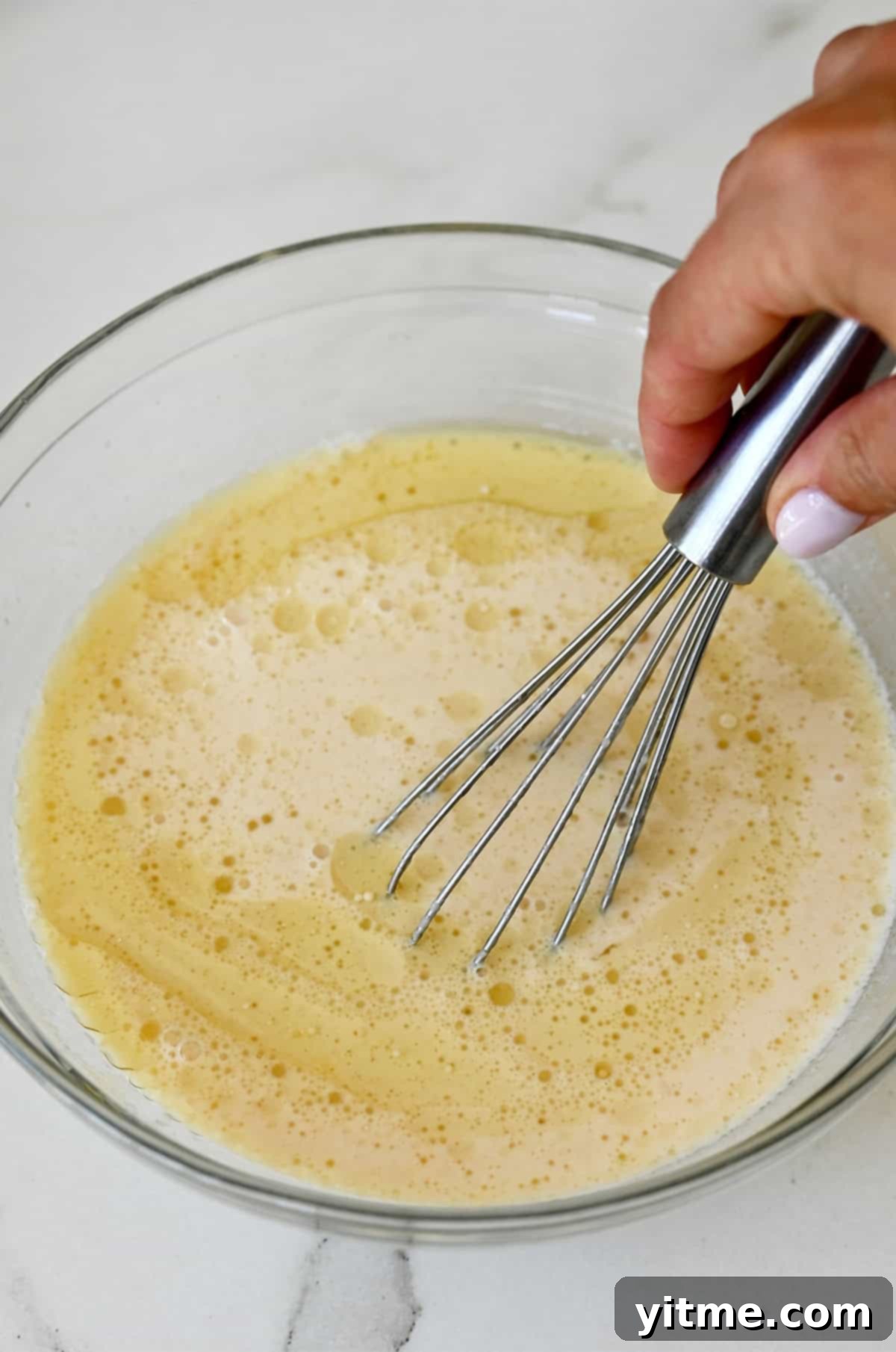 Whisking applesauce with milk, egg, oil and vanilla for pancakes.