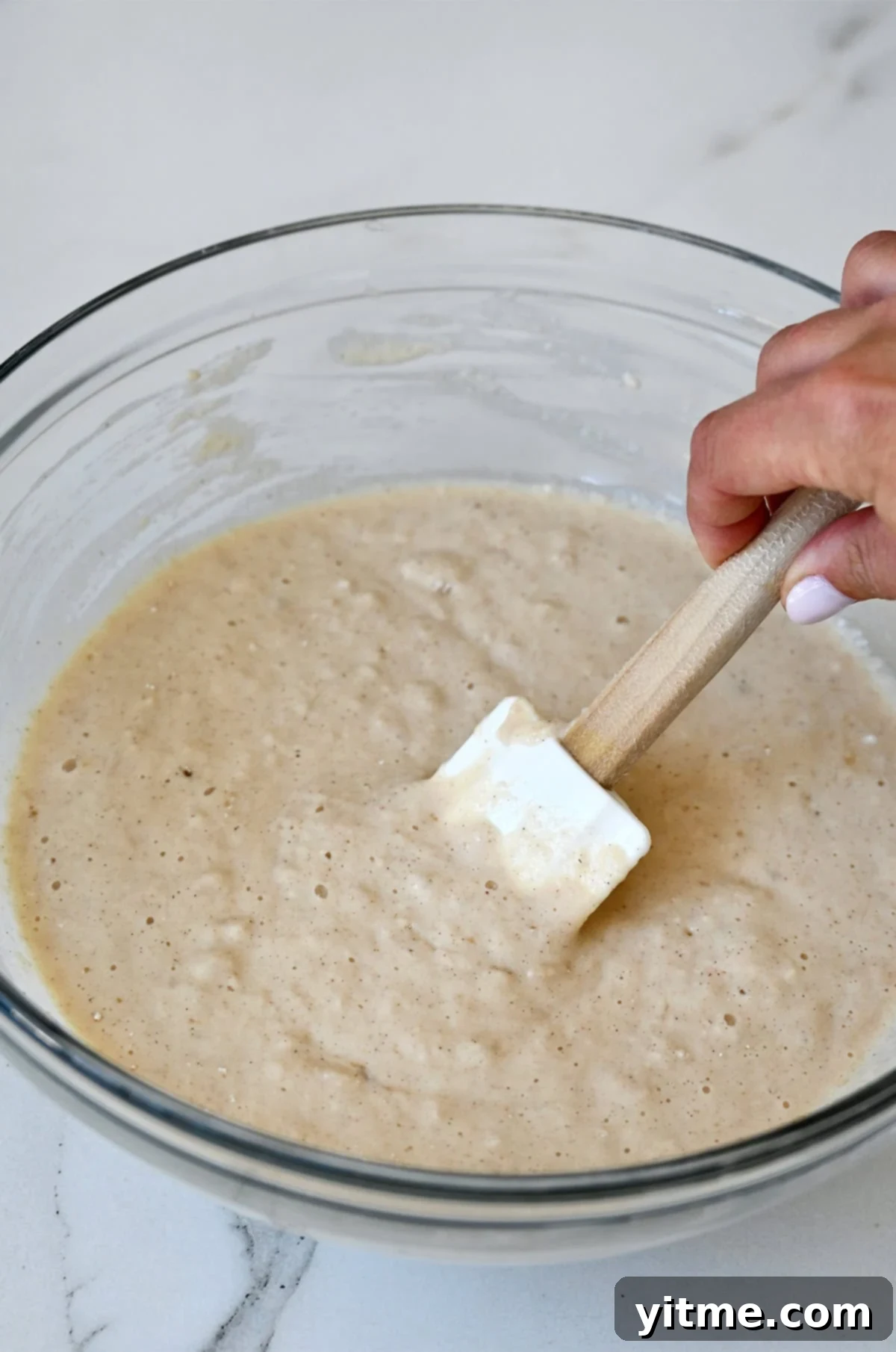 Lumpy applesauce pancake batter in a glass bowl.