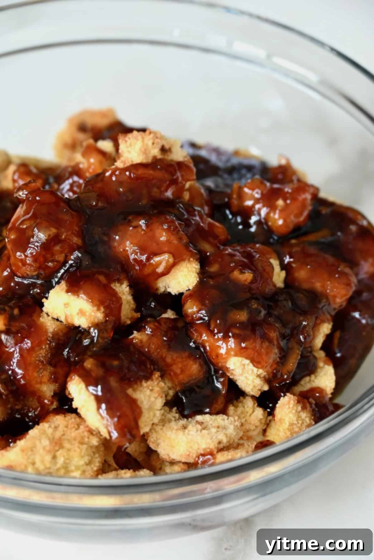 Orange sauce being poured over baked chicken pieces