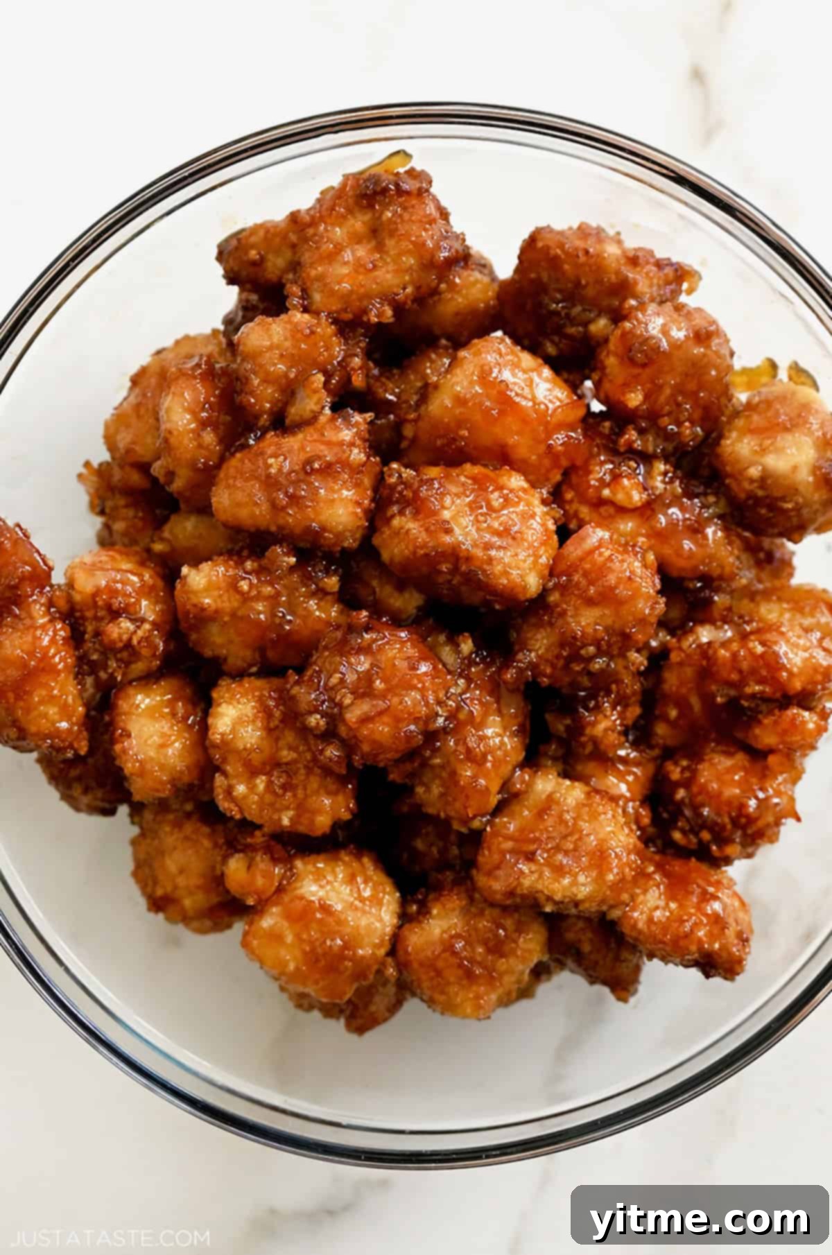 Baked chicken coated in orange sauce in a bowl