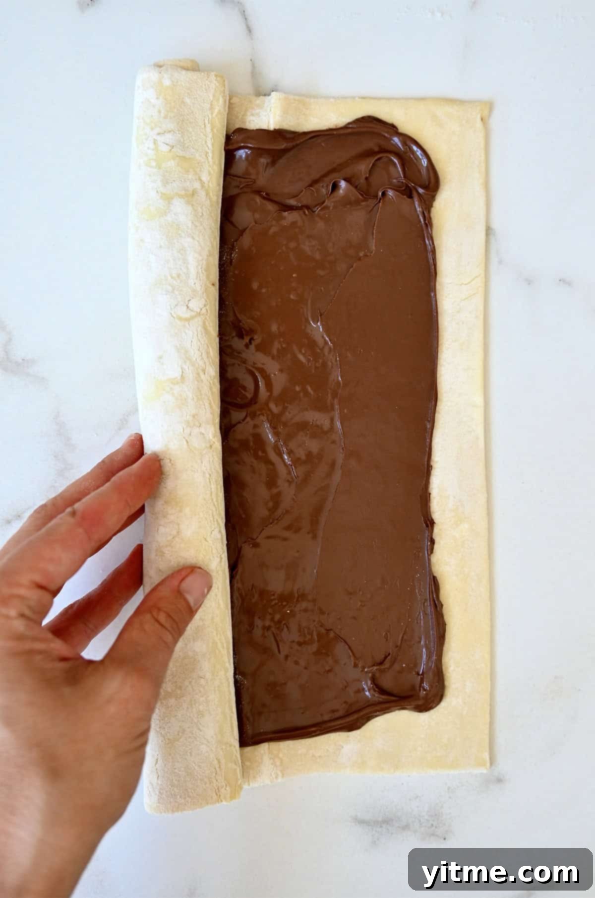 Decadent Chocolate Swirls 5 Rolling Nutella puff pastry into a log.