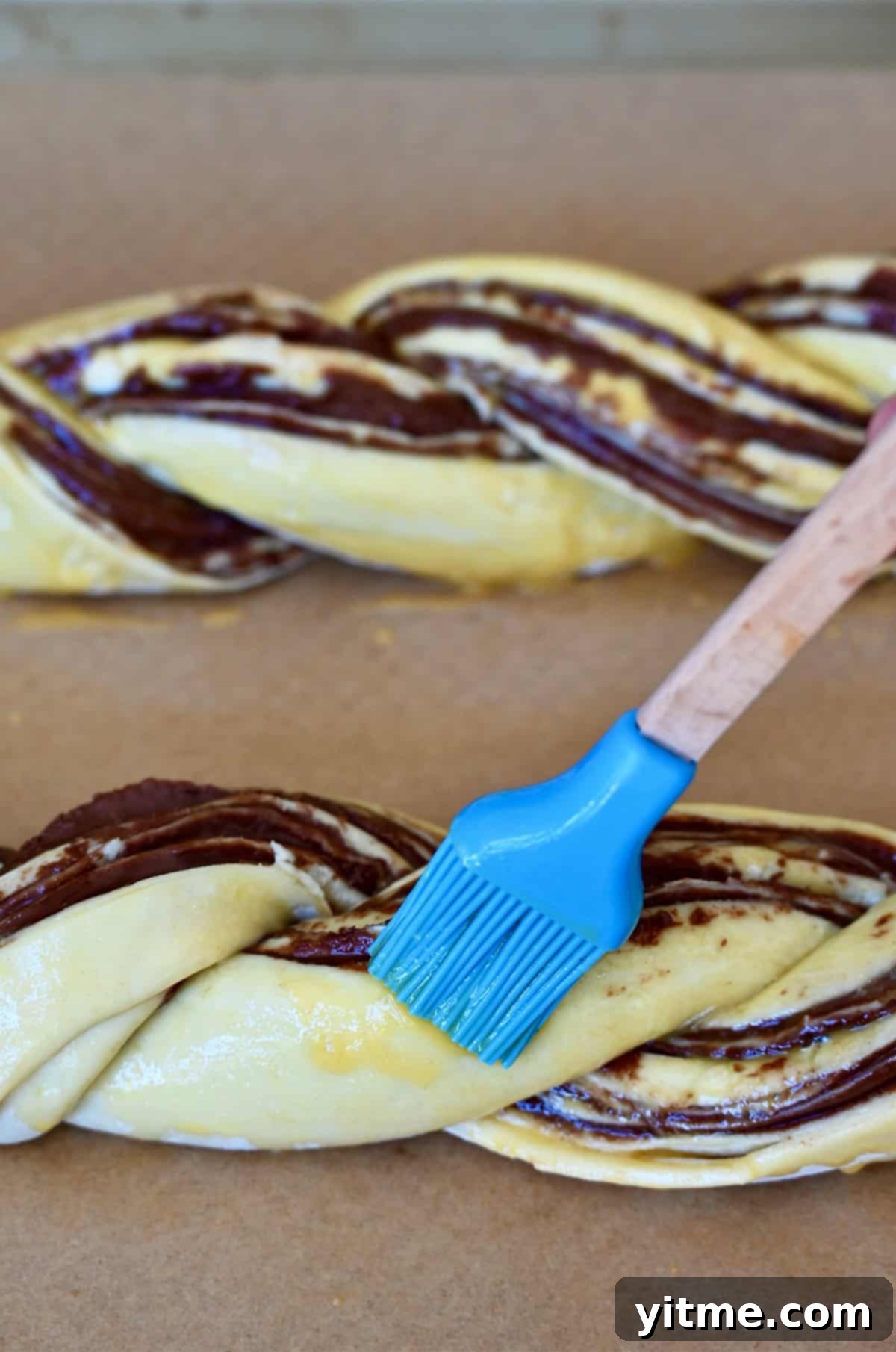Decadent Chocolate Swirls 9 Brushing egg wash on puff pastry braids.