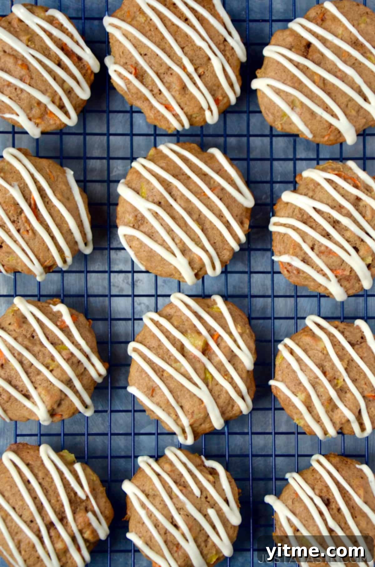 Carrot cake cookies drizzled with icing on a cooling rack.