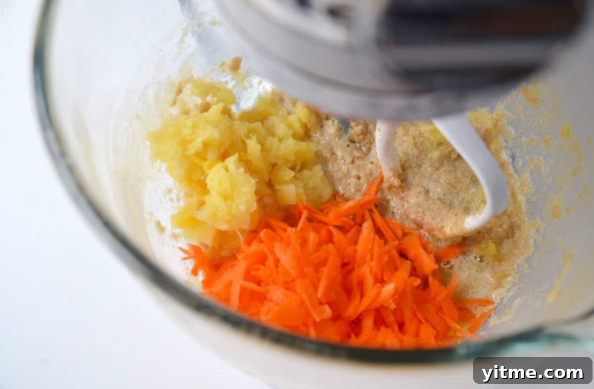 Butter, brown sugar, crushed pineapple and grated carrots in the bowl of a stand mixer.