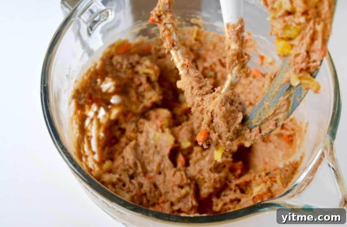 Carrot cake cookie batter in the bowl of stand mixer.