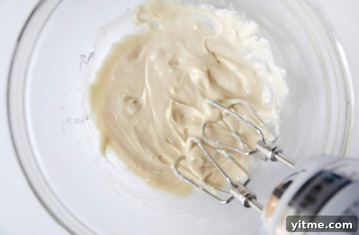 Cream cheese icing in a glass mixing bowl.