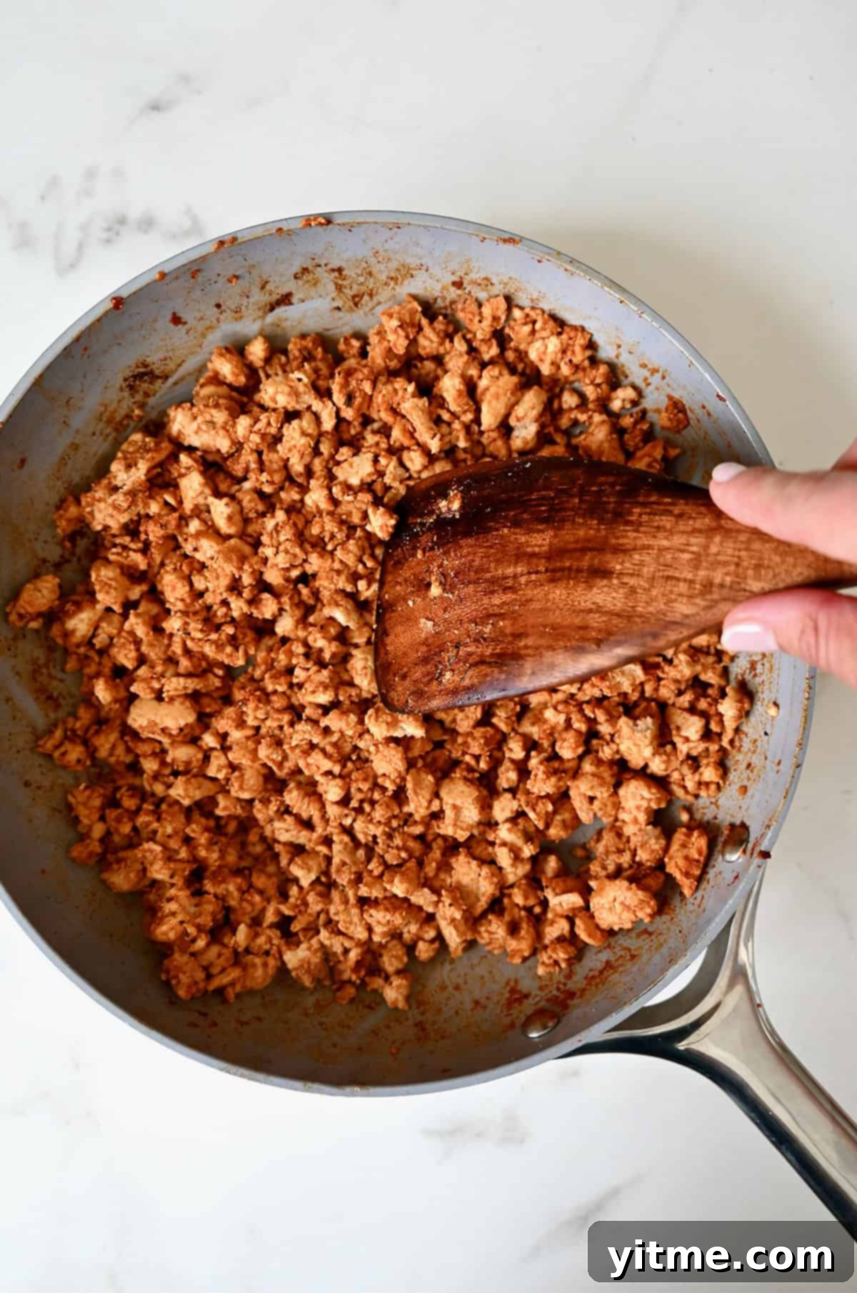 Deliciously Healthy Stuffed Zucchini Boats 5 Browned turkey taco meat in a skillet with a wooden spatula.