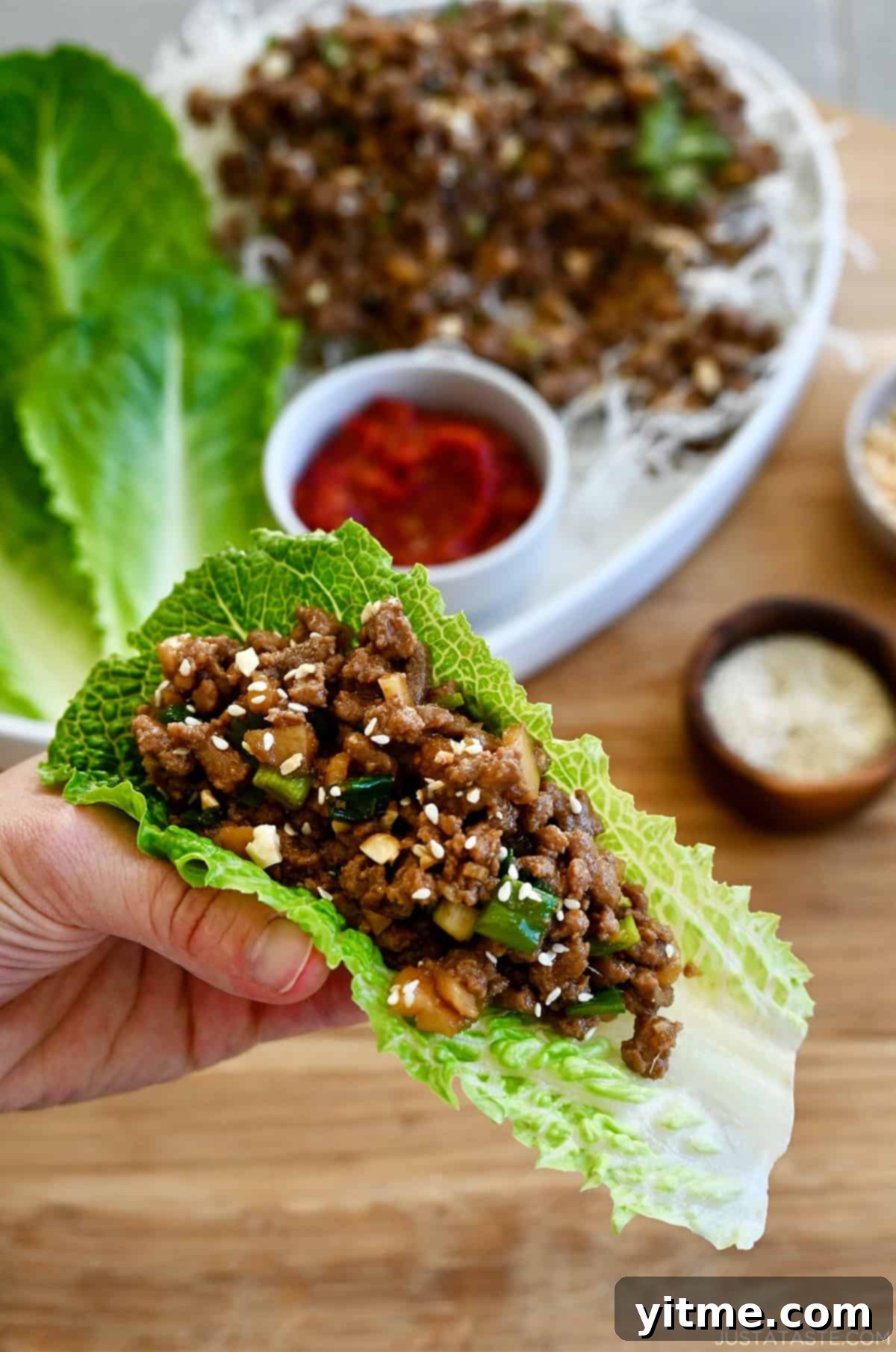 A delicious ground chicken lettuce wrap held in a hand, showcasing the vibrant ingredients and fresh lettuce cup.