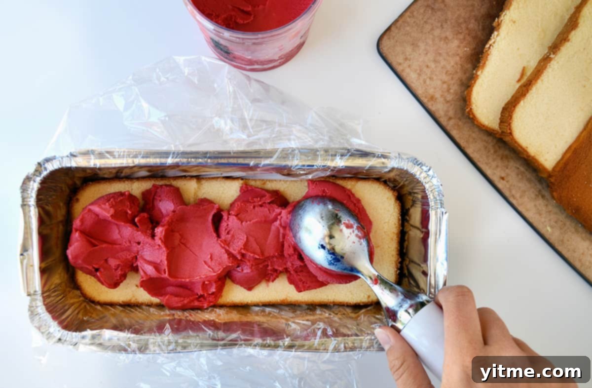 Scooping raspberry sorbet onto pound cake in an aluminum tray.