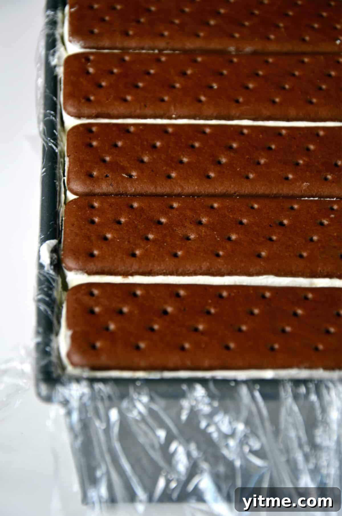 Ice cream sandwich cake in a loaf pan lined with plastic wrap.