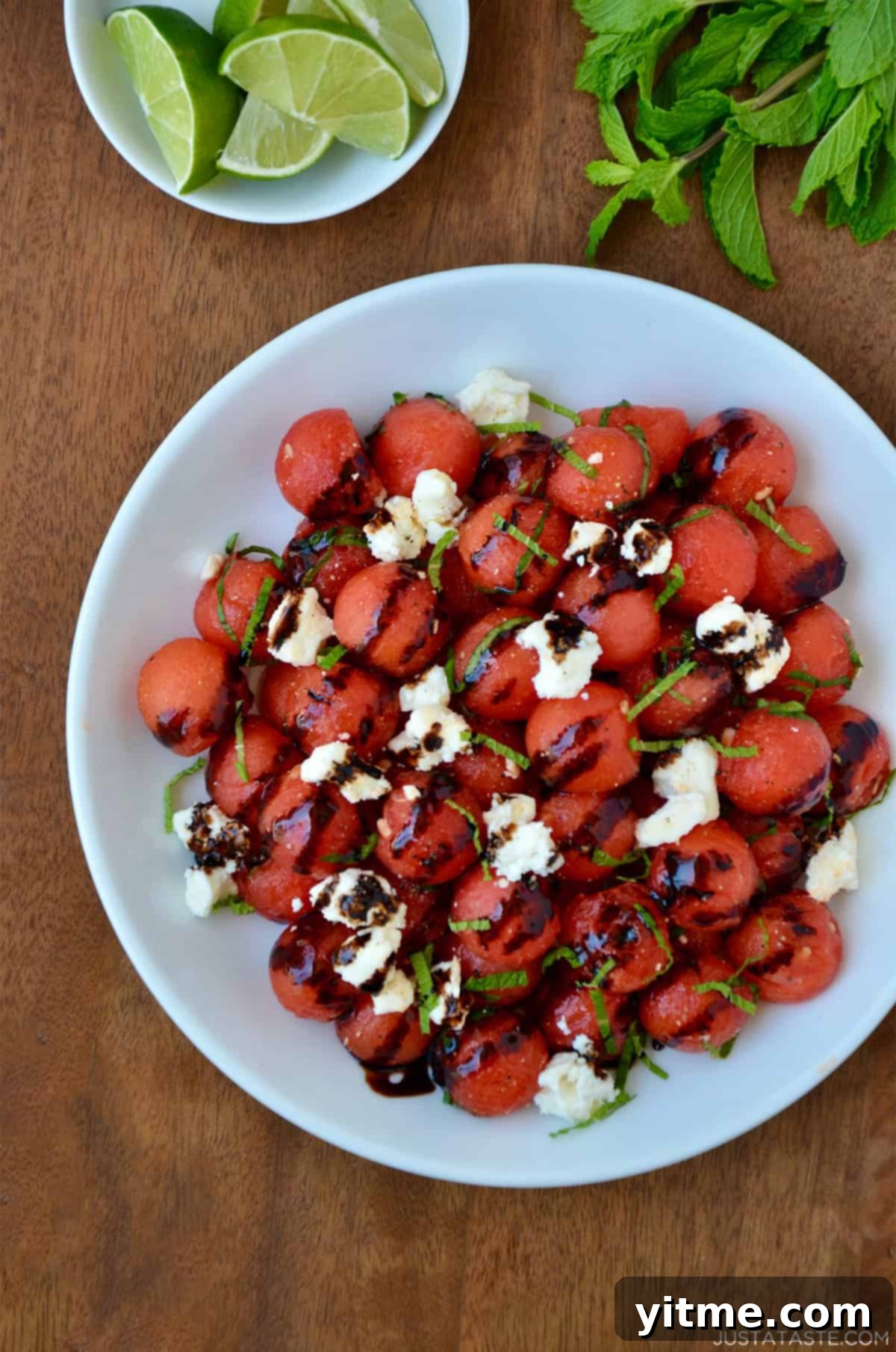 Watermelon salad with balsamic syrup, crumbled feta cheese, and fresh mint in a white serving bowl