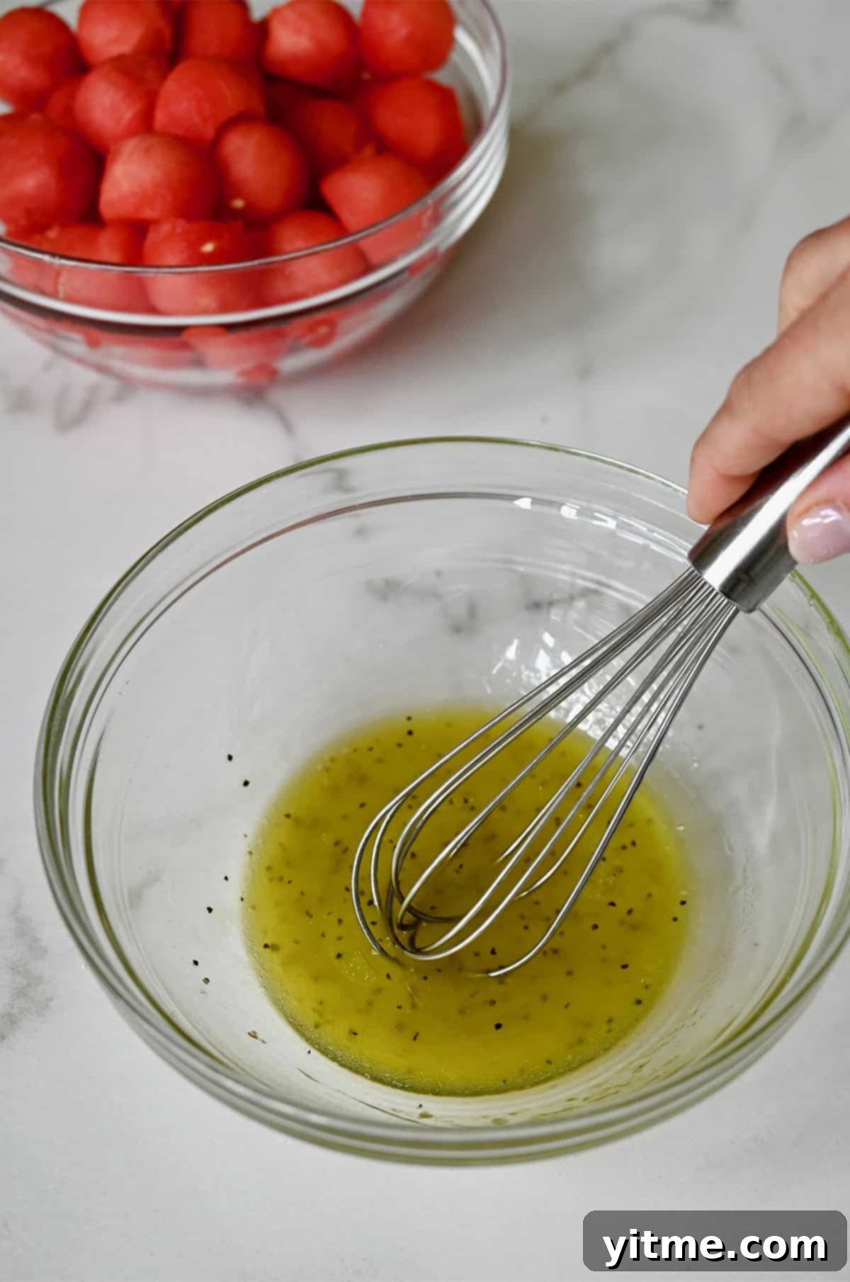 Olive oil, lime juice, salt, and pepper being whisked together in a small bowl