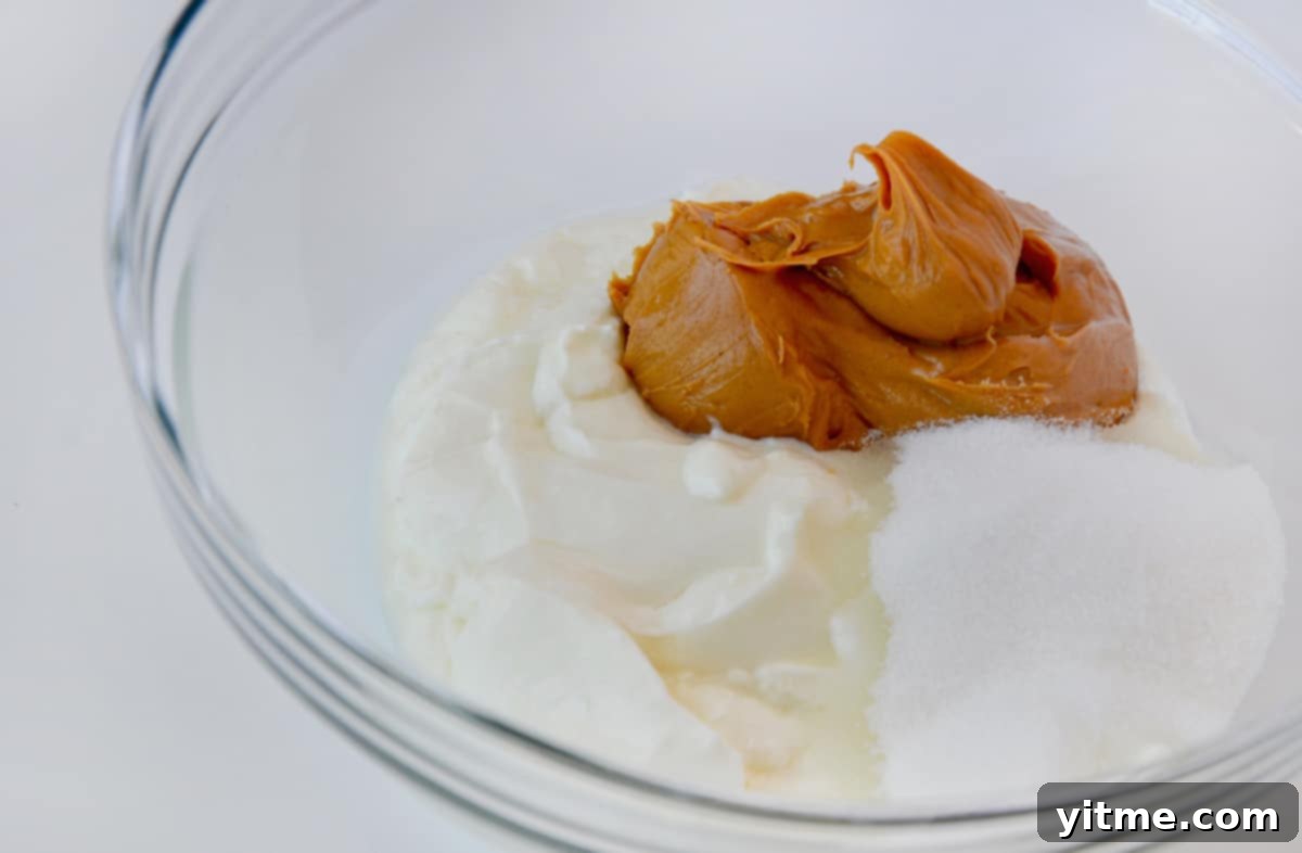 Creamy Peanut Butter Fro-Yo Pops 4 A clear bowl containing yogurt, peanut butter and sugar.