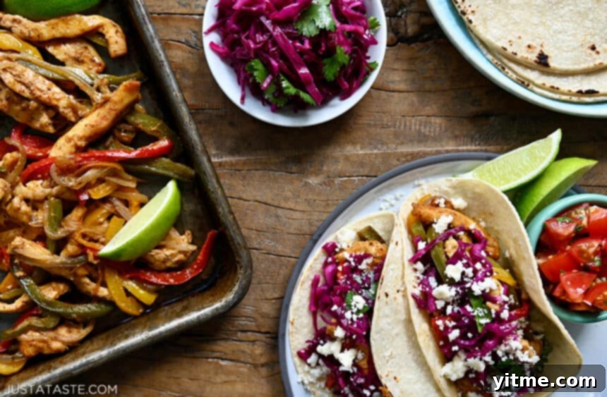 A top-down view of easy Sheet Pan Chicken Fajitas next to a plate of corn tortilla tacos