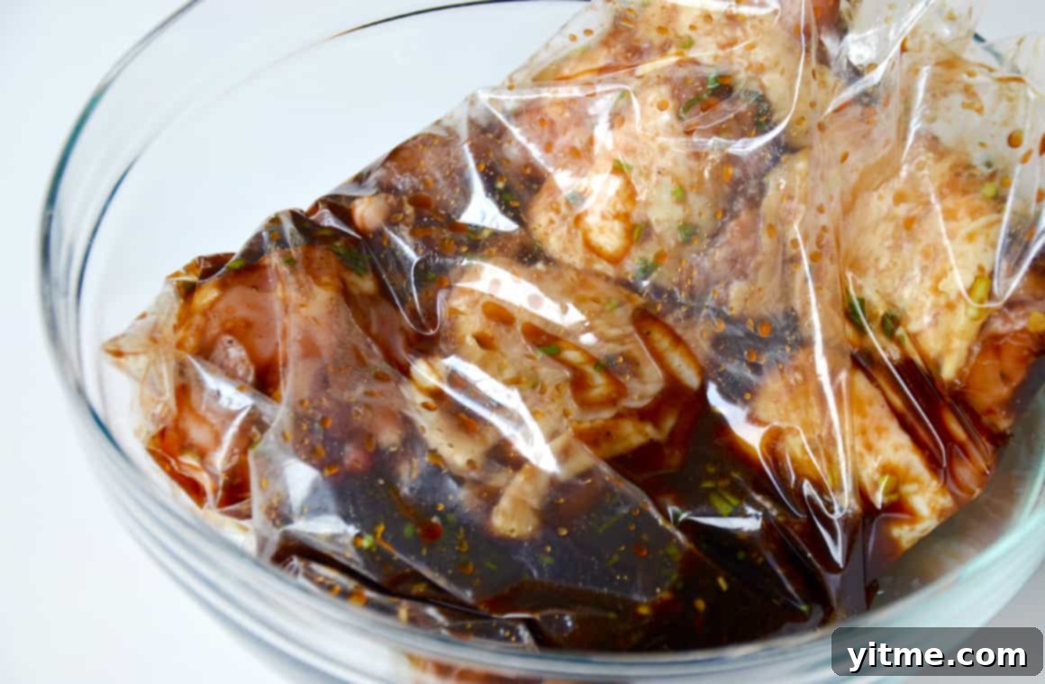 A clear bowl containing a plastic bag with marinating poultry