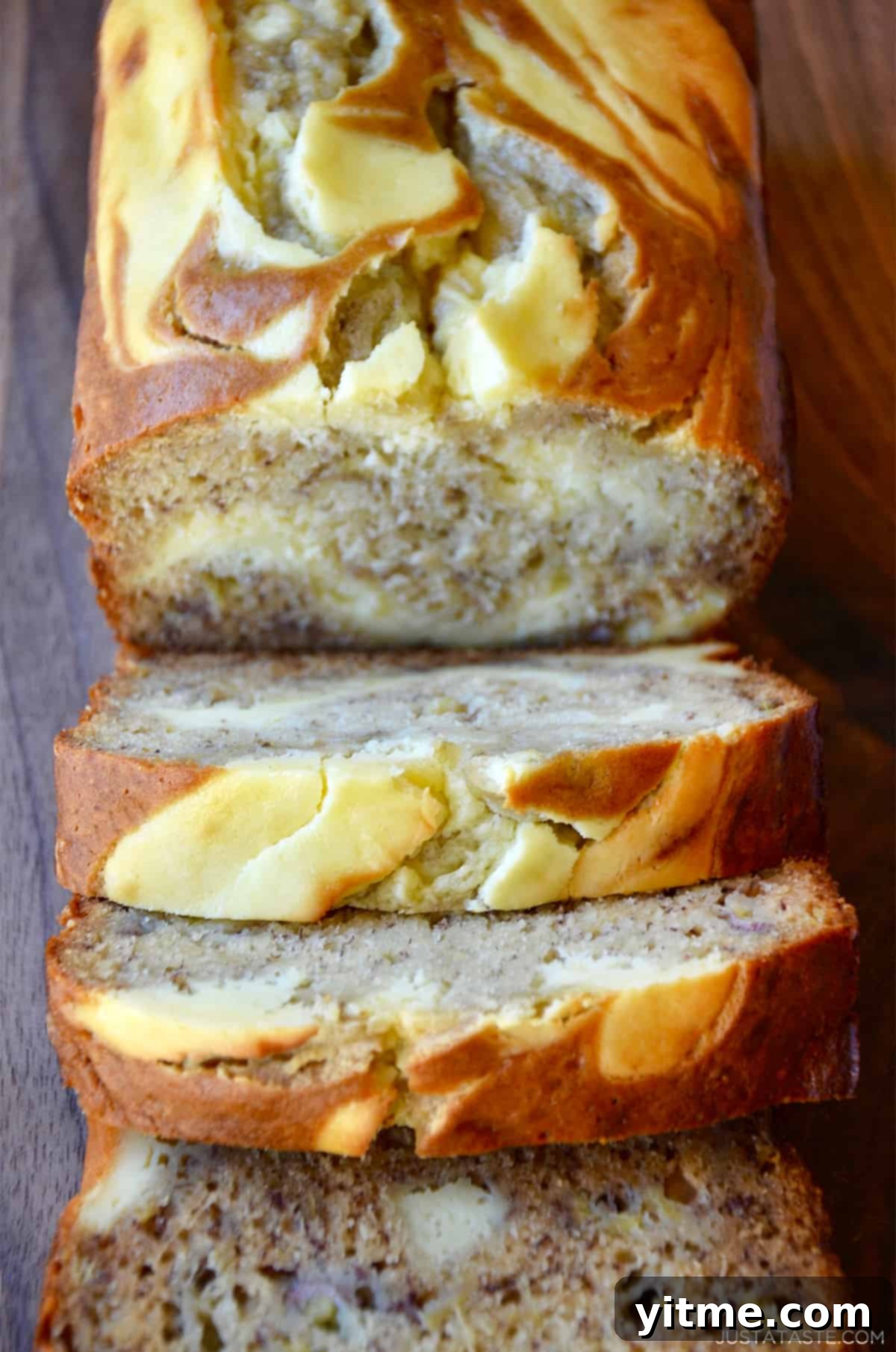 A loaf of cream cheese banana bread cut into perfect slices, showcasing the beautiful swirl of banana bread and cream cheese filling.