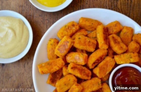 Golden Butternut Bites 7 A white plate with butternut squash tots, ketchup and mustard