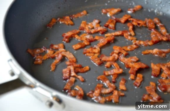 Bacon pieces cooking in a nonstick pan
