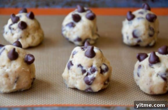 Mounds of chocolate chip cookie dough spaced out on a baking sheet