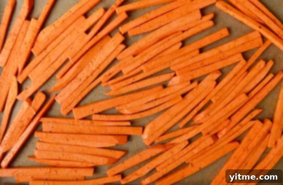 Uncooked sweet potato fries on a lined baking sheet