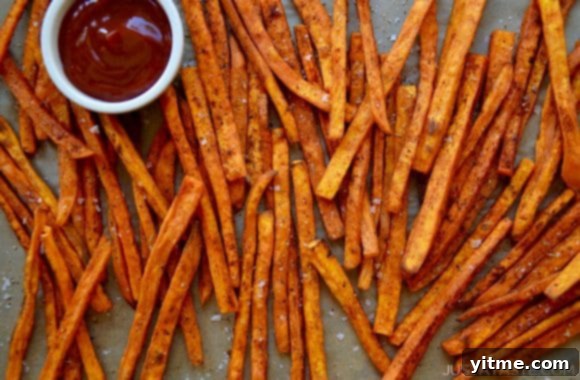 Sweet potato fries scattered on a baking sheet