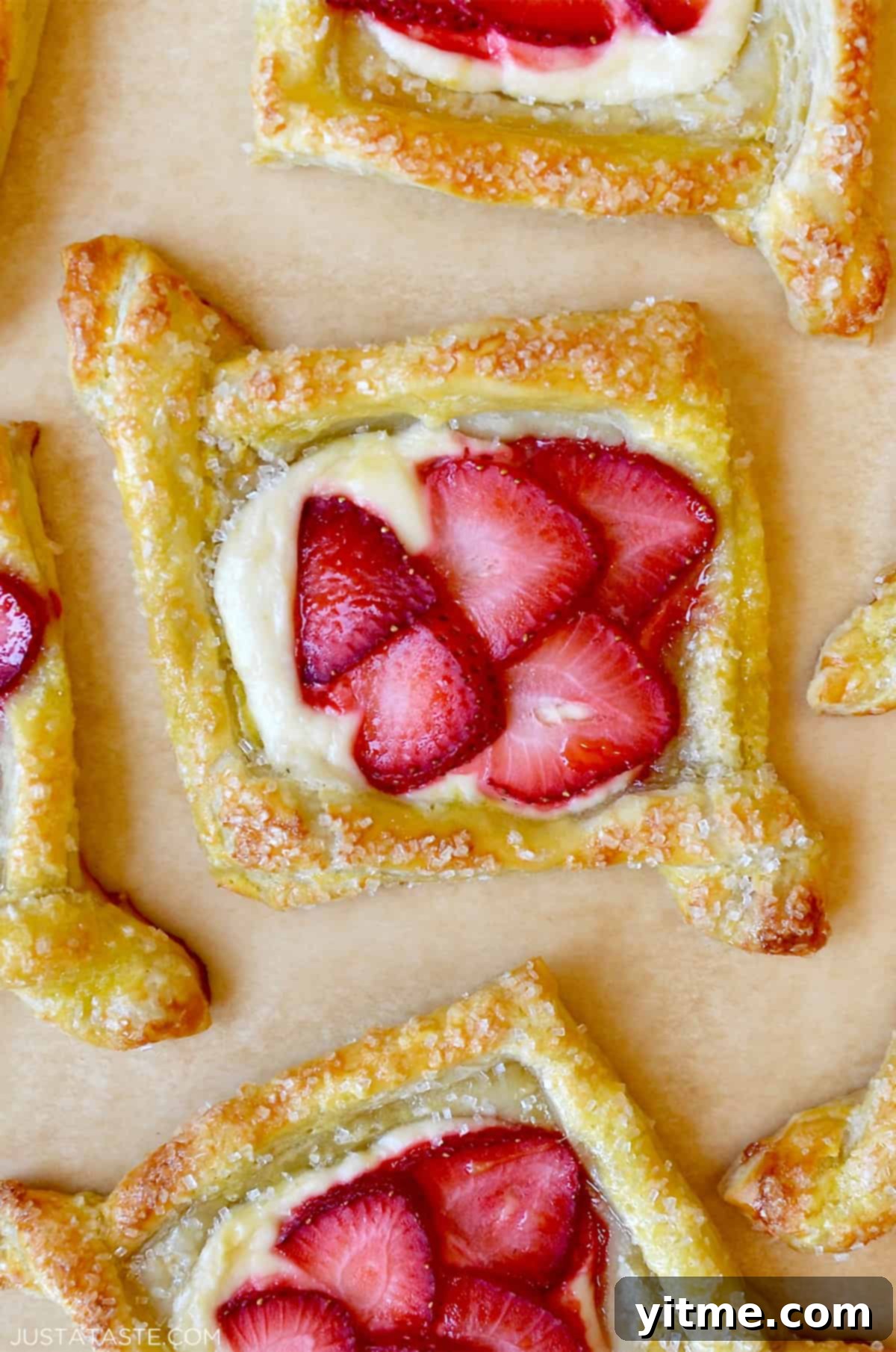 Cheese danish topped with fresh strawberries and sprinkled with sanding sugar, highlighting its bakery-quality finish.