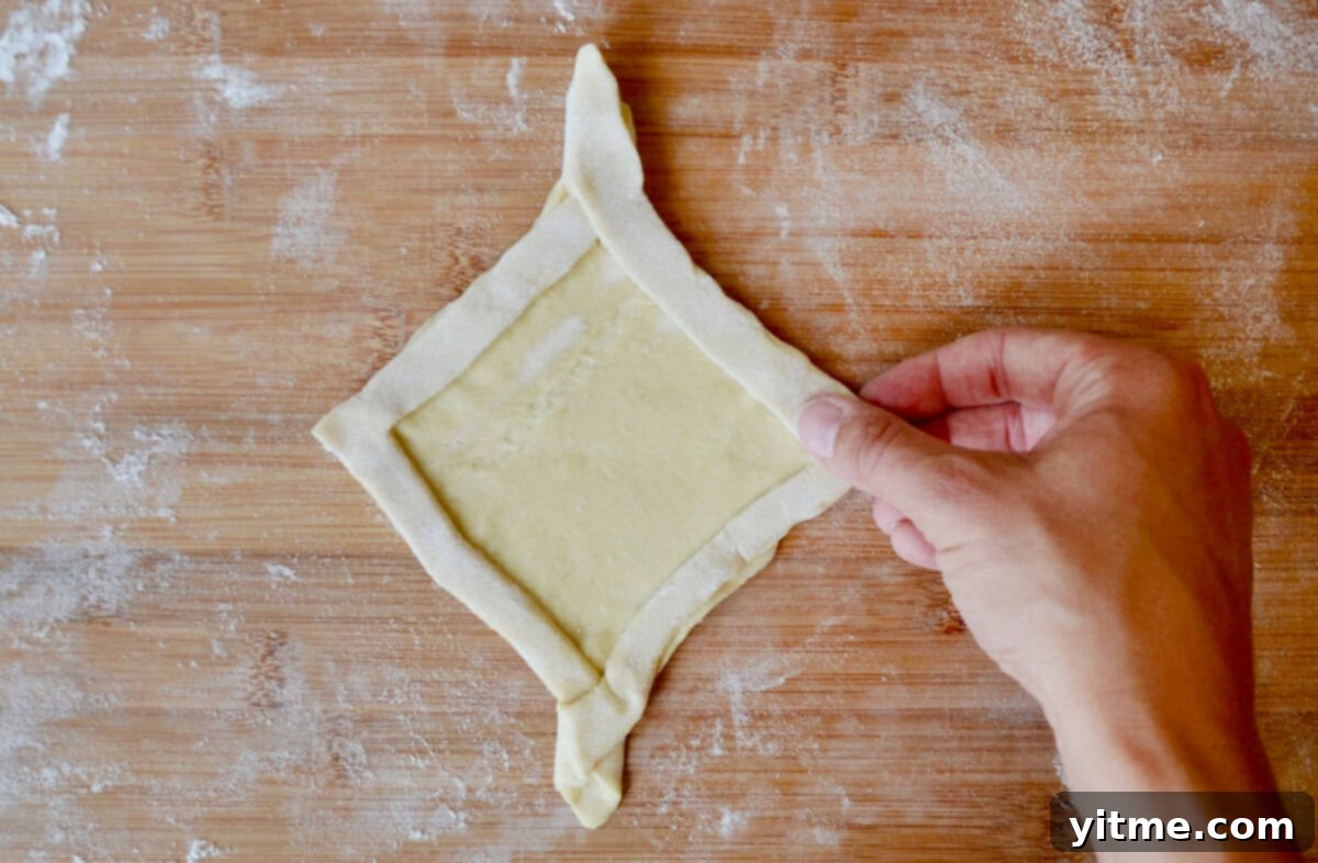 Diamond-shaped Danish puff pastry dough on a cutting board, showcasing the finished folded shape.
