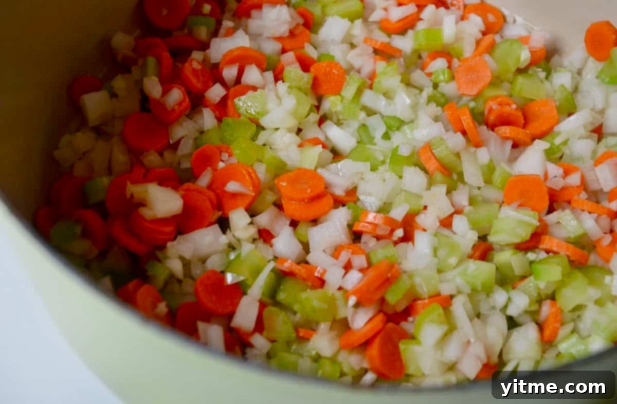 Sautéed carrots, onion, and celery in the bottom of a large stockpot, forming a flavorful aromatic base.