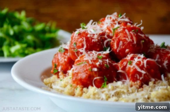A white bowl filled with fluffy quinoa and savory baked turkey meatballs, generously topped with marinara sauce.