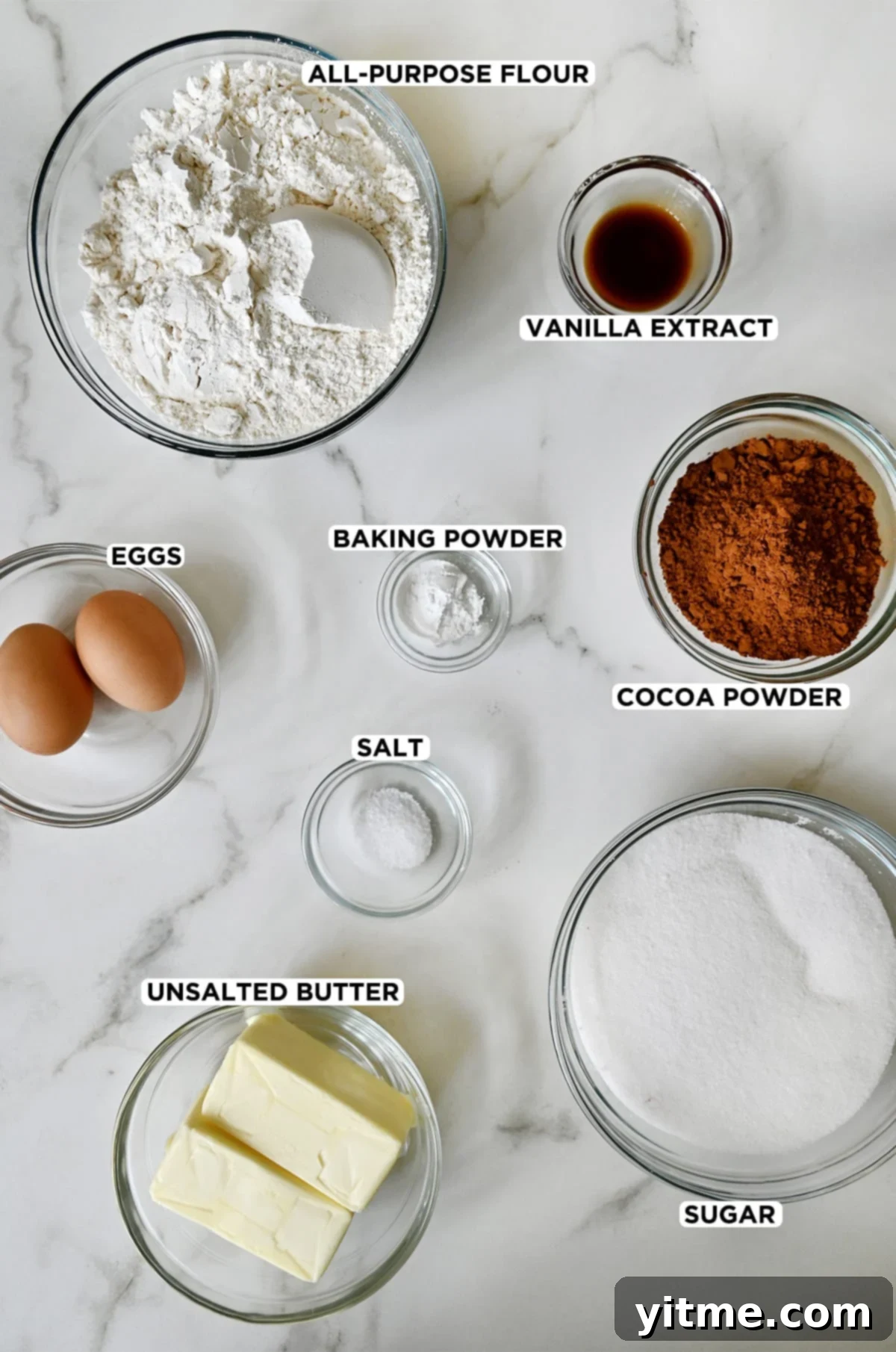 Ingredients for chocolate sugar cookies: vanilla extract, cocoa powder, sugar, butter, salt, baking powder, eggs, and flour