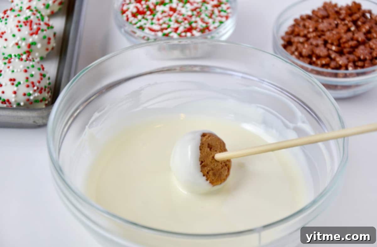 Dipping a gingerbread cookie ball into melted white chocolate.