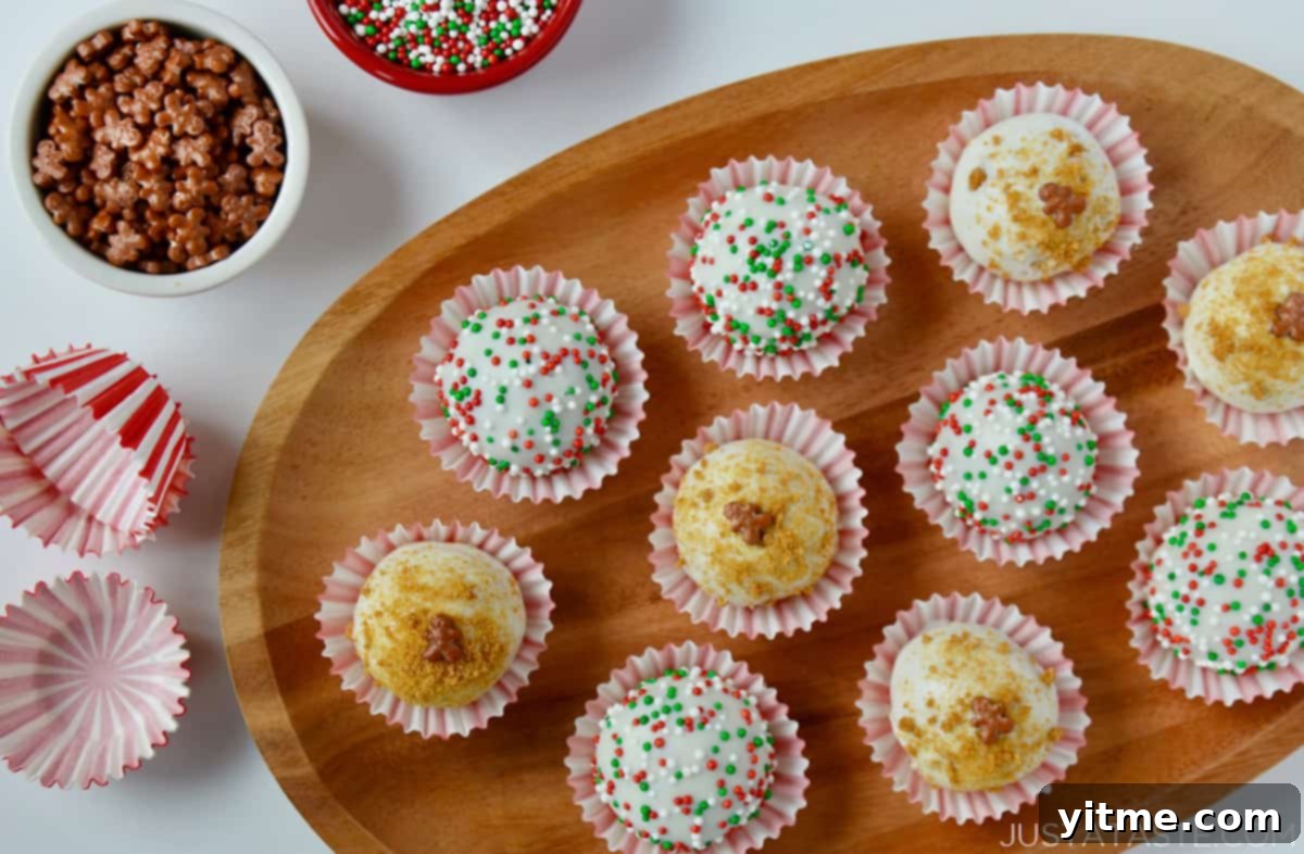 A wooden platter holding white chocolate- and sprinkle-covered gingerbread cookie balls in striped wrappers.