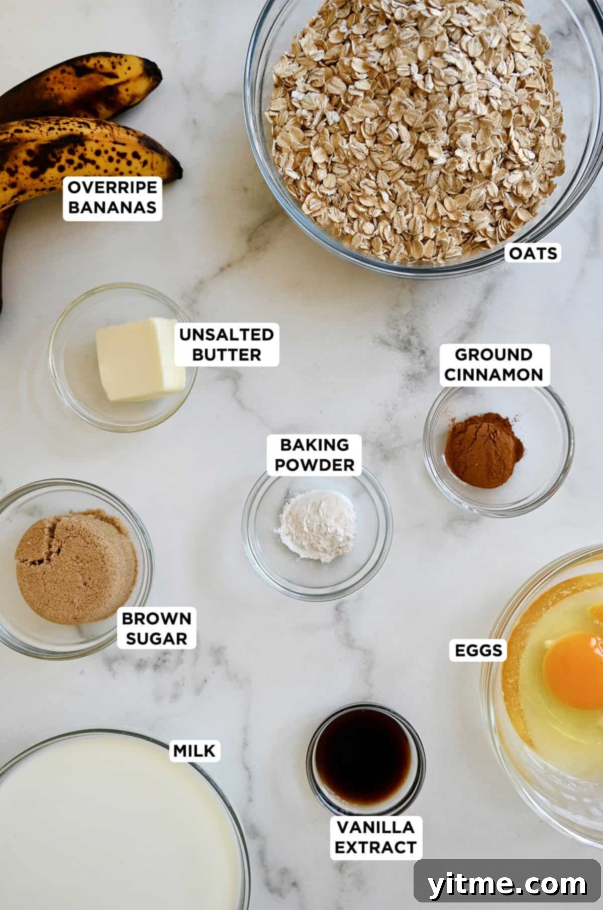 Ingredients to make baked oatmeal, including old-fashioned rolled oats, butter, brown sugar, eggs, overripe bananas, baking powder, milk and cinnamon.