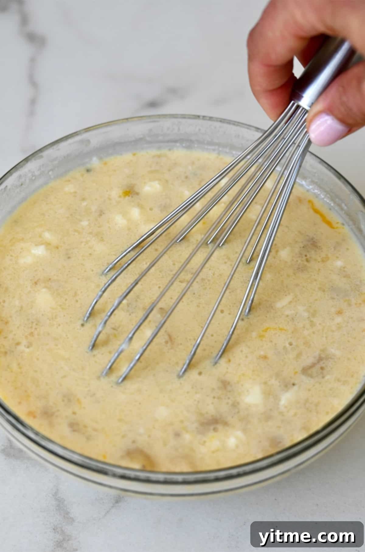Wet ingredients for baked oatmeal being whisked together in a glass bowl.