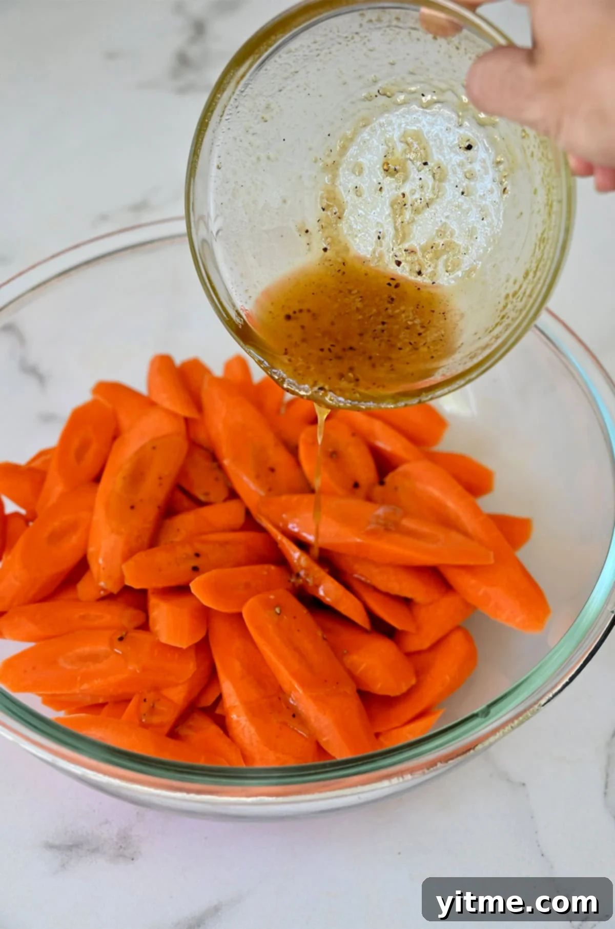 Honey-Glazed Roasted Carrots 6 Honey-olive oil mixture being poured over sliced carrots.