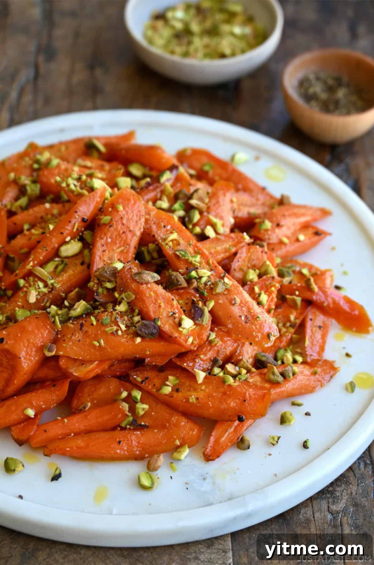 Honey-Glazed Roasted Carrots 8 Caramelized honey roasted carrots garnished with crushed pistachios on a serving platter.