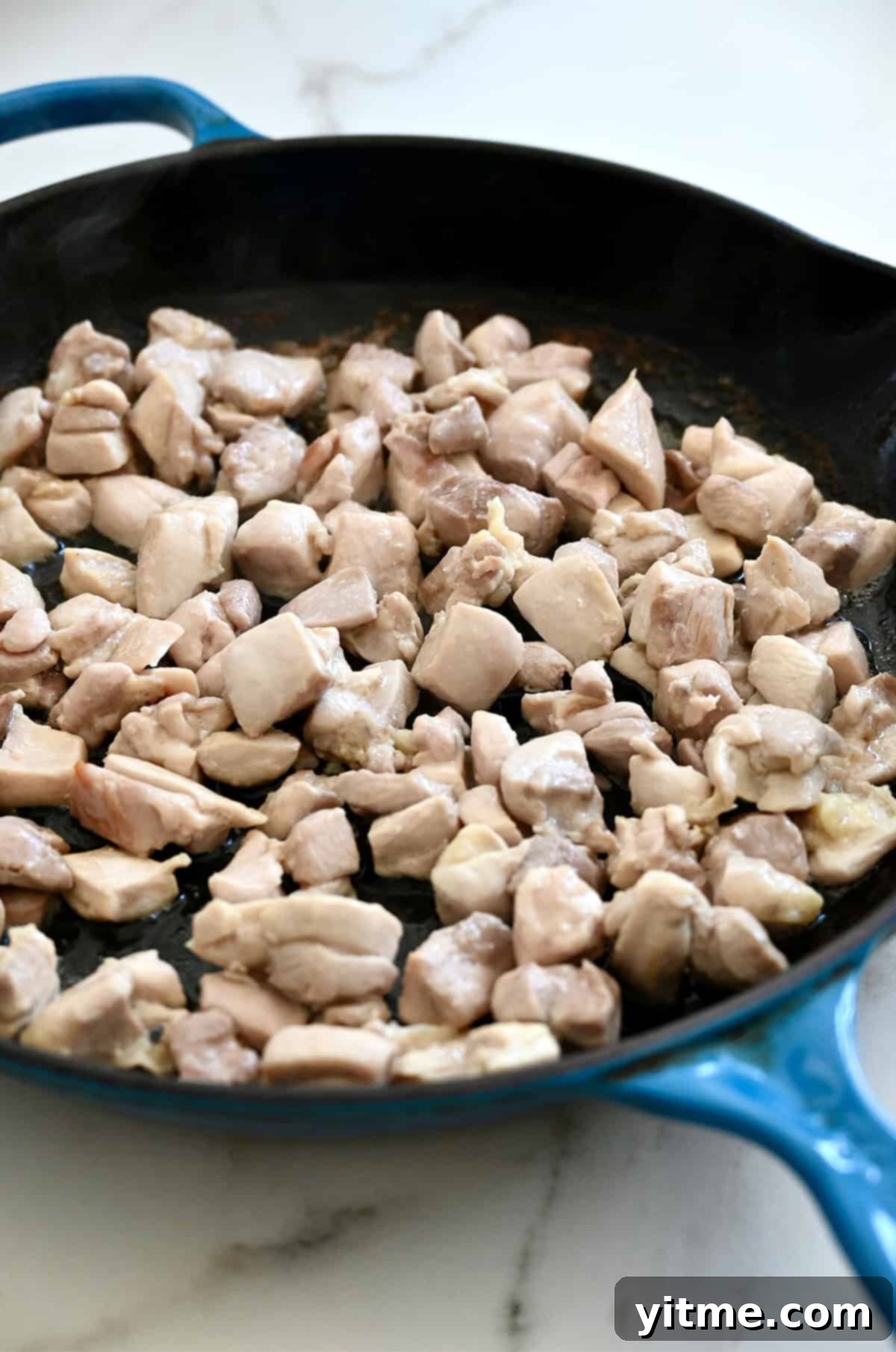 Chicken thighs cooking in a skillet.