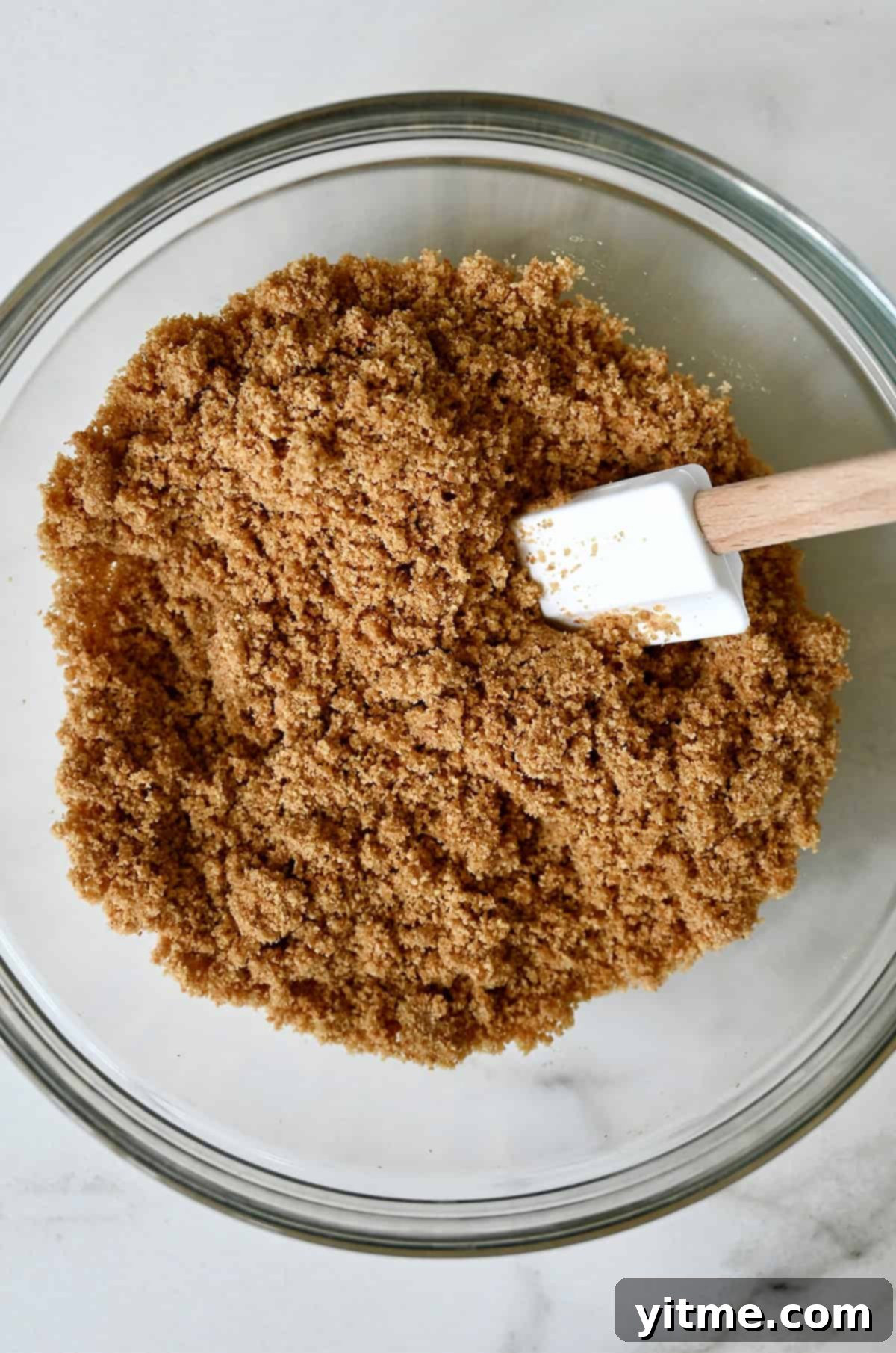 Two-ingredient graham cracker crust in a bowl with a spatula.