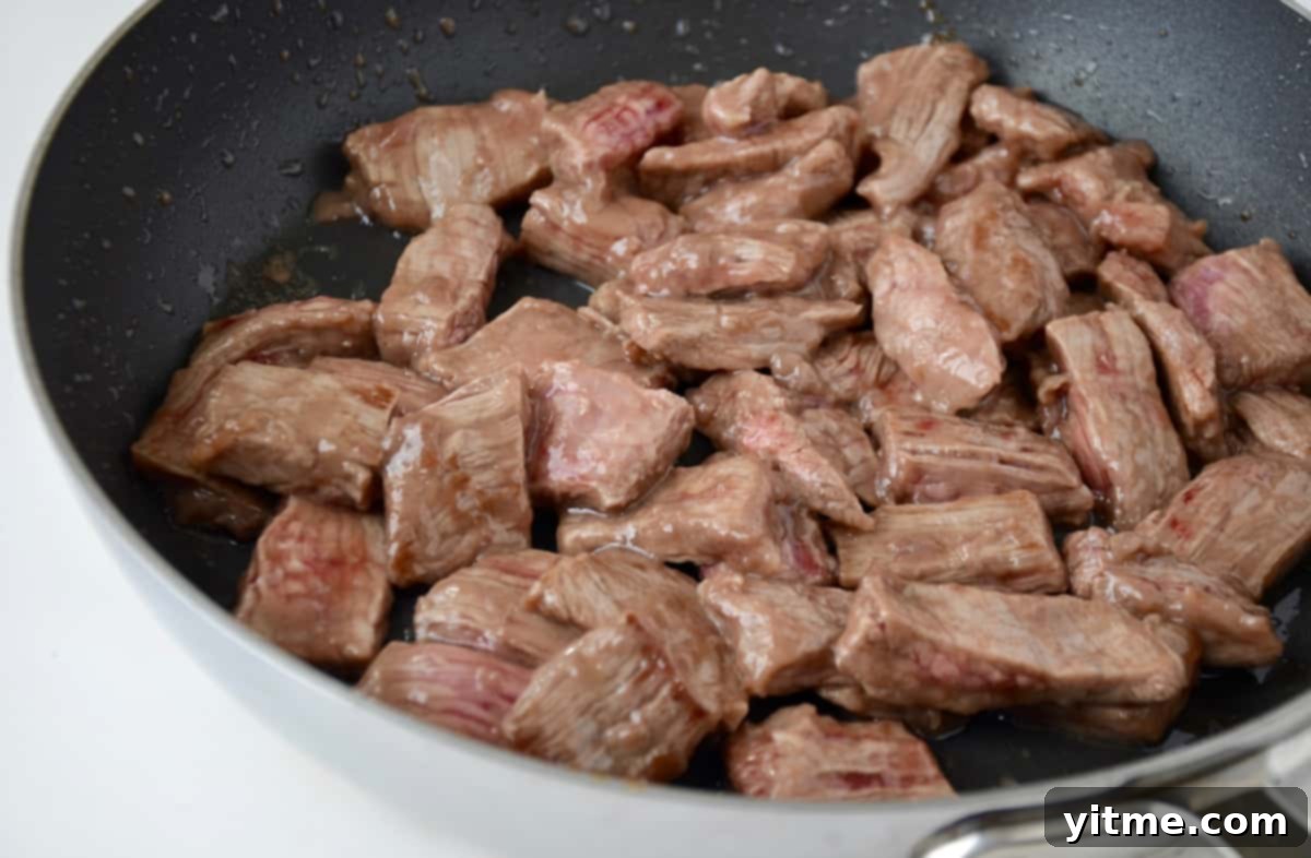 Beef coated in cornstarch cooking in a skillet