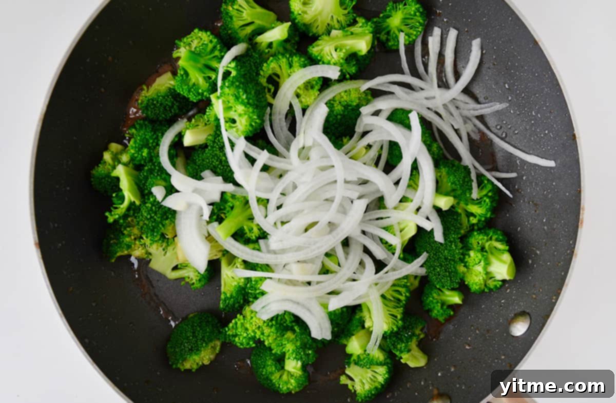 Broccoli and onions sautéing in a skillet