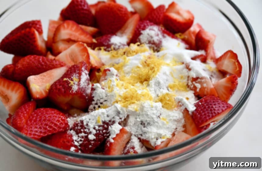 Sliced strawberries, cornstarch and lemon zest in a clear bowl
