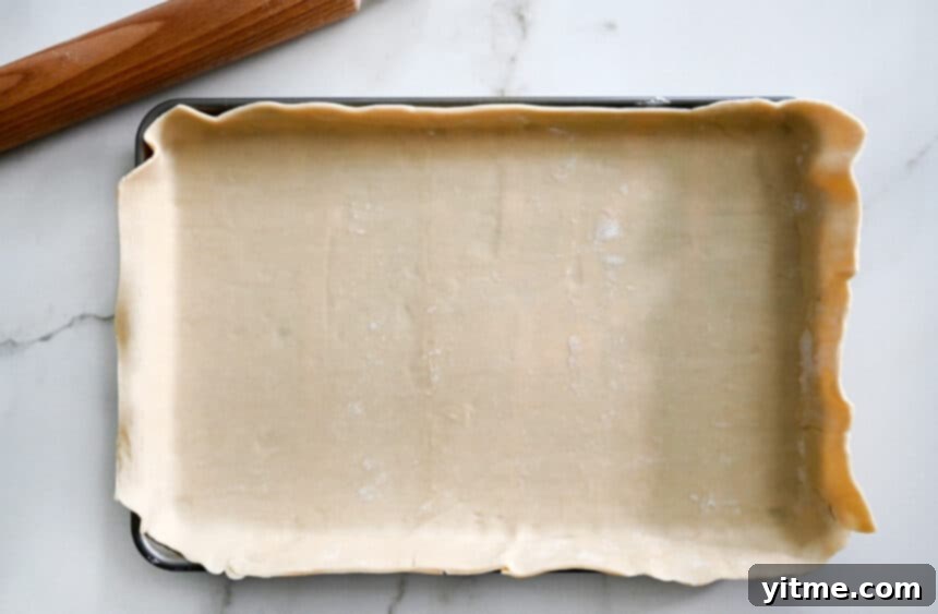 A baking sheet topped with pie dough next to a rolling pin