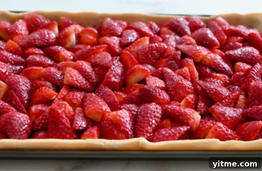 A close-up view of vibrant, sliced strawberries atop unbaked dough