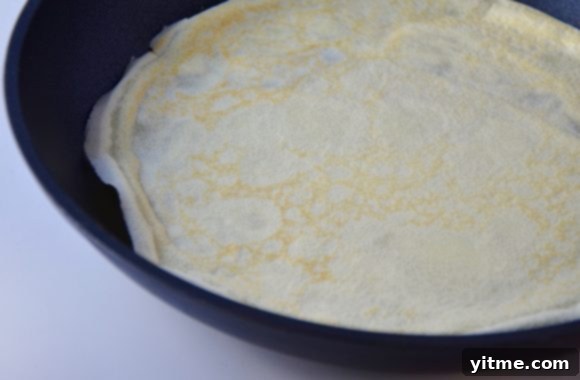 Strawberry Dream Crêpes 4 Image of a crepe being cooked in a nonstick sauté pan.