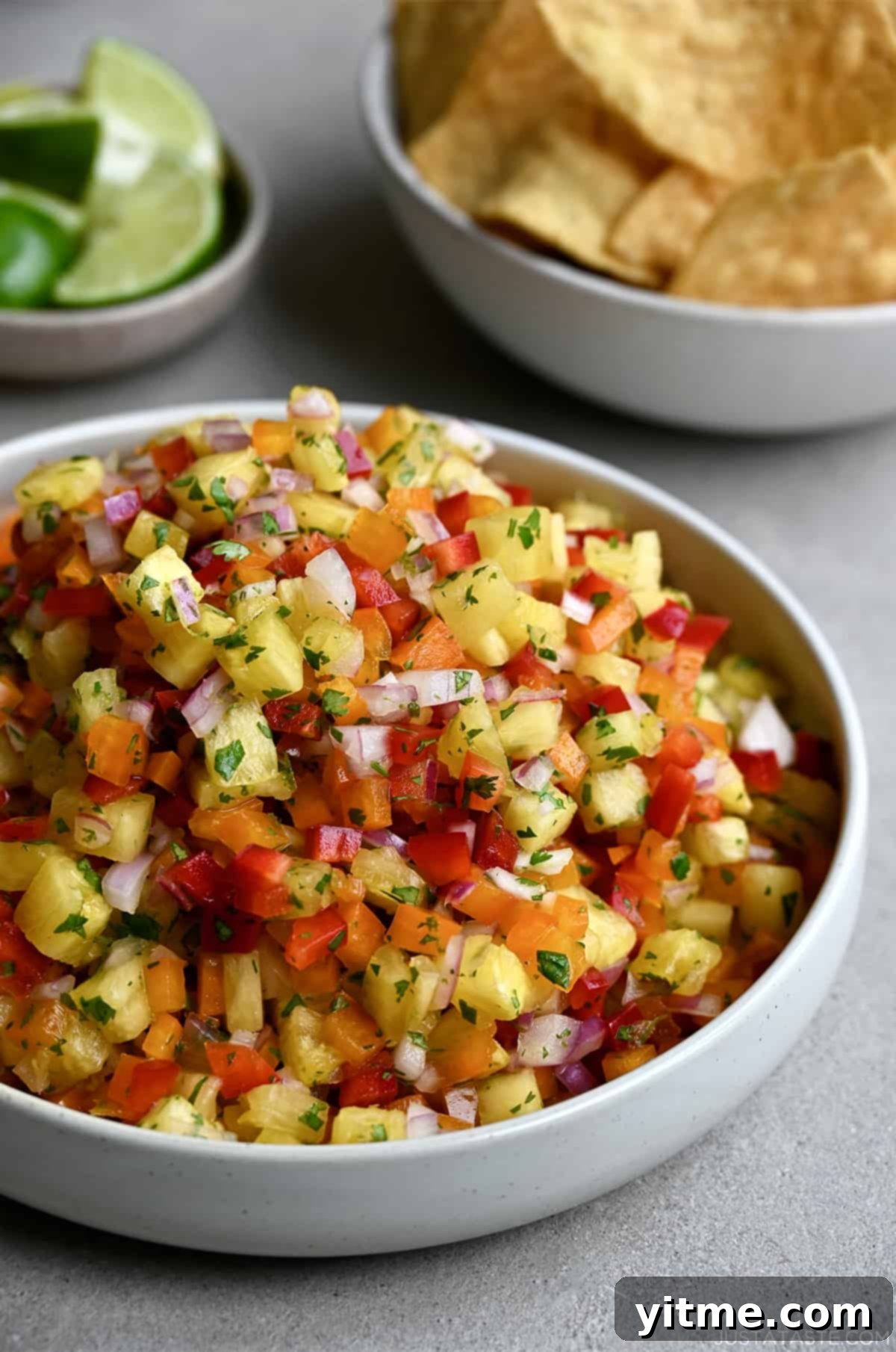 A vibrant white bowl of pineapple salsa, garnished with fresh cilantro, showcasing its appealing texture and color.