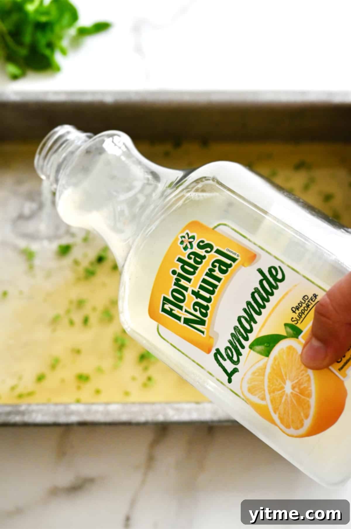 A hand holding a carton of Florida's Natural Lemonade over a baking sheet.