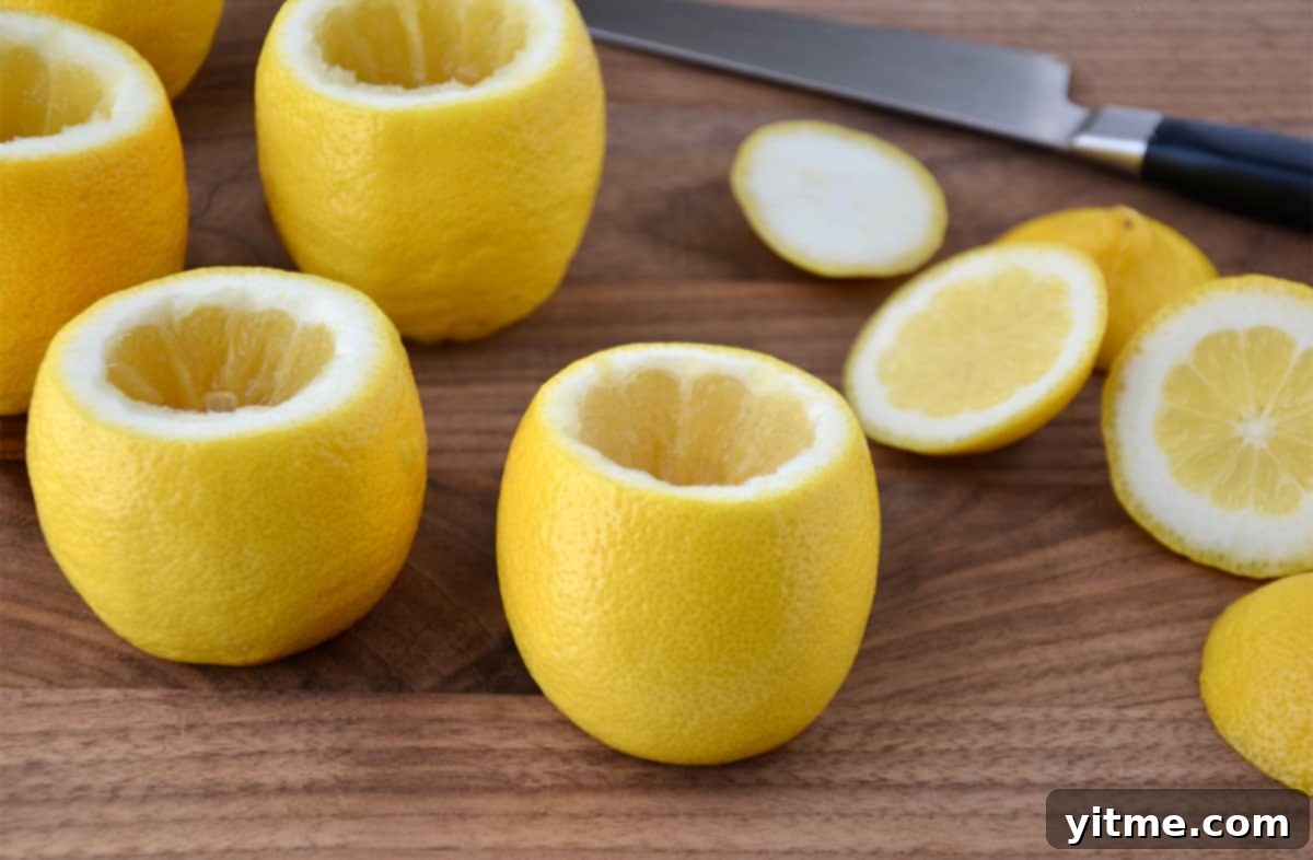 Hollowed out lemons on a wood surface next to a sharp knife.