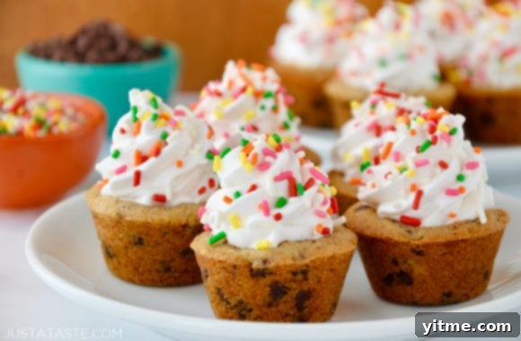 Muffin Tin Chocolate Chip Cookie Treats 7 A white plate containing Chocolate Chip Cookie Cups with bowls of sprinkles and chocolate chips in the background