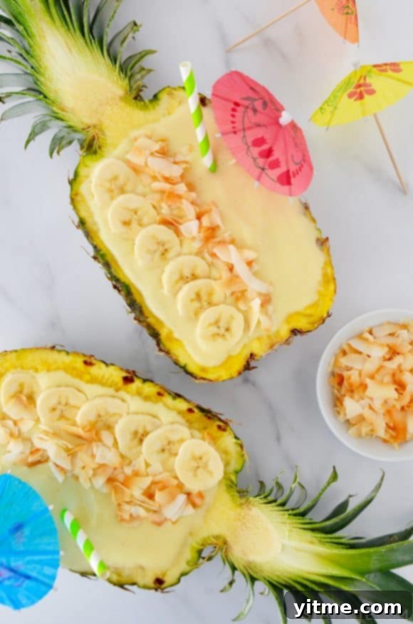Tropical Paradise Smoothie 2 Pineapples hollowed out and filled with smoothie mixture topped with sliced bananas and coconut